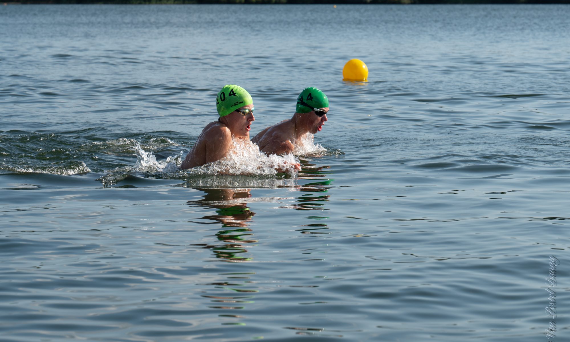 Twee zwemmers met groene badmuts op het BK openwaterzwemmen.